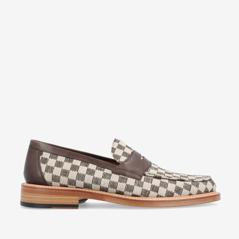 A loafer shoe with a checkered fabric design, brown leather accents, and a wooden sole.