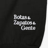 Black fabric with white embroidered text that reads Botas & Zapatos & Gente.