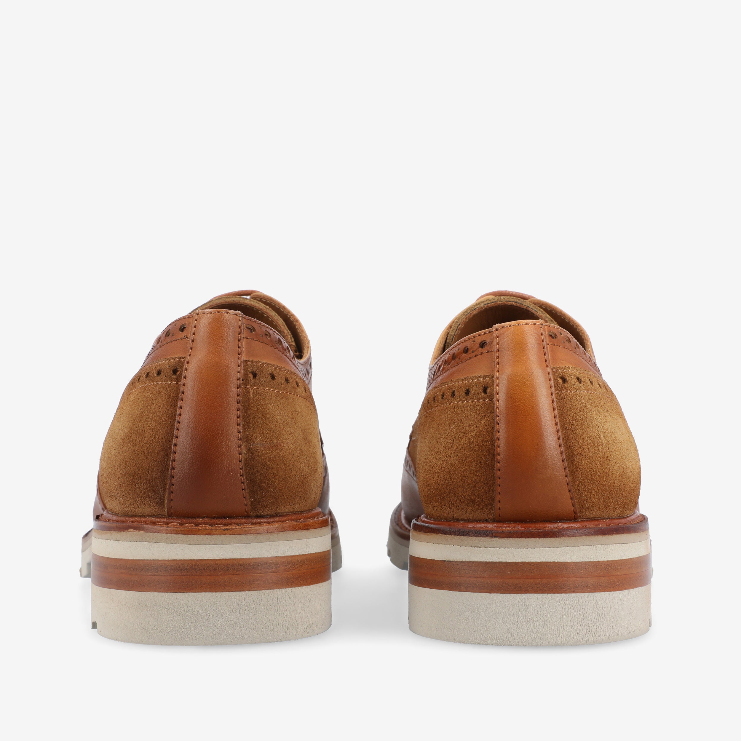 Rear view of a pair of brown leather and suede brogue shoes with white, brown, and tan layered soles.