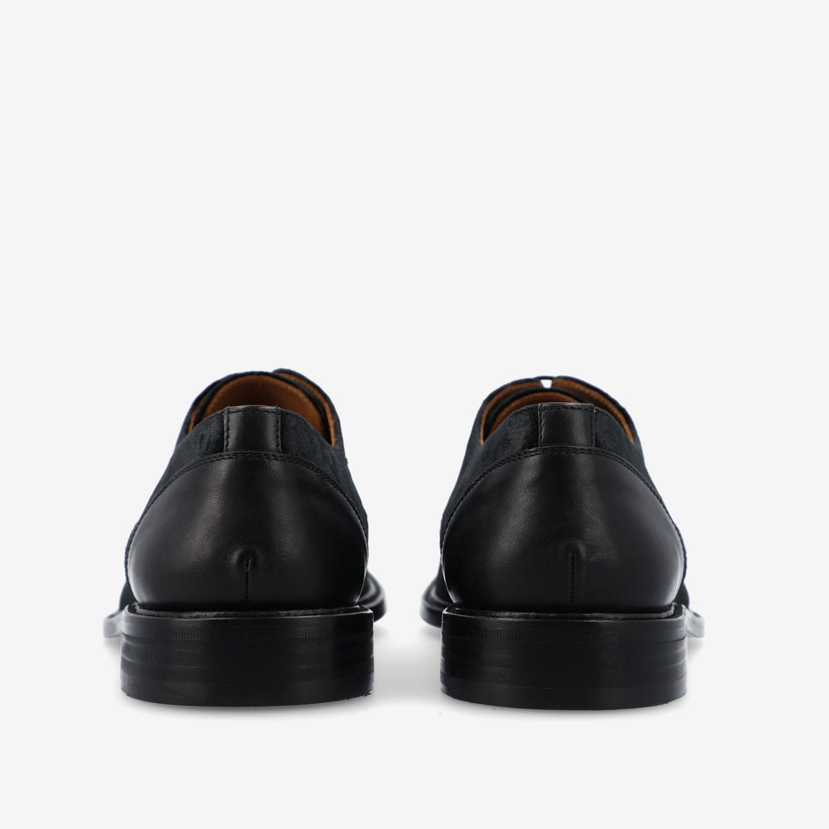 Rear view of a pair of black leather dress shoes with a polished finish on a white background.