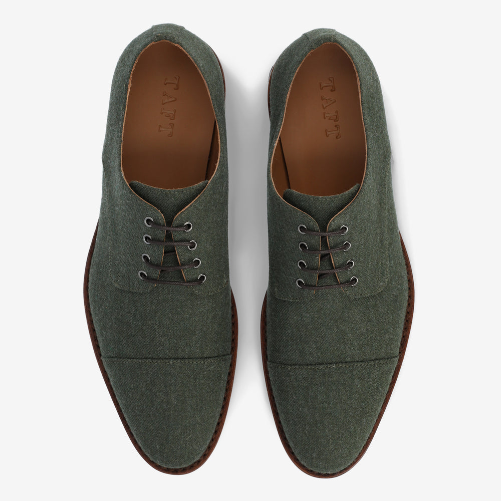 A pair of green lace-up shoes with brown soles viewed from the top on a white background. The shoes have a textured fabric surface.