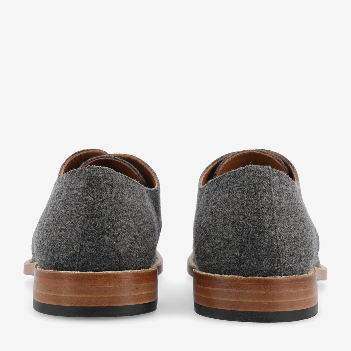 Rear view of a pair of gray wool shoes with brown wooden soles, photographed against a plain white background.