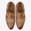 Pair of brown leather shoes with woven patterns on the sides and buckle closures, viewed from above.