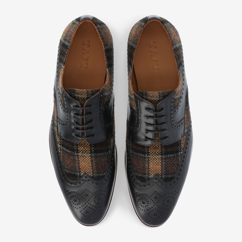 A pair of men's dress shoes with a combination of leather brogue detailing and multicolored plaid fabric, top view.