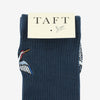 A pair of navy blue socks with embroidered crane designs, packaged under a label reading TAFT with a bird graphic.