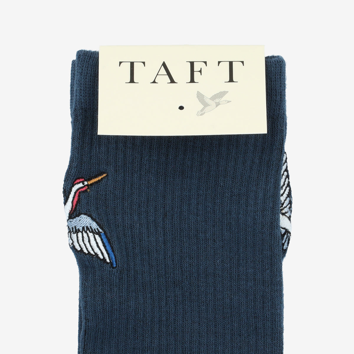 A pair of navy blue socks with embroidered crane designs, packaged under a label reading TAFT with a bird graphic.