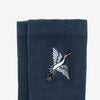 A pair of dark blue socks with an embroidered flying bird design near the cuff.