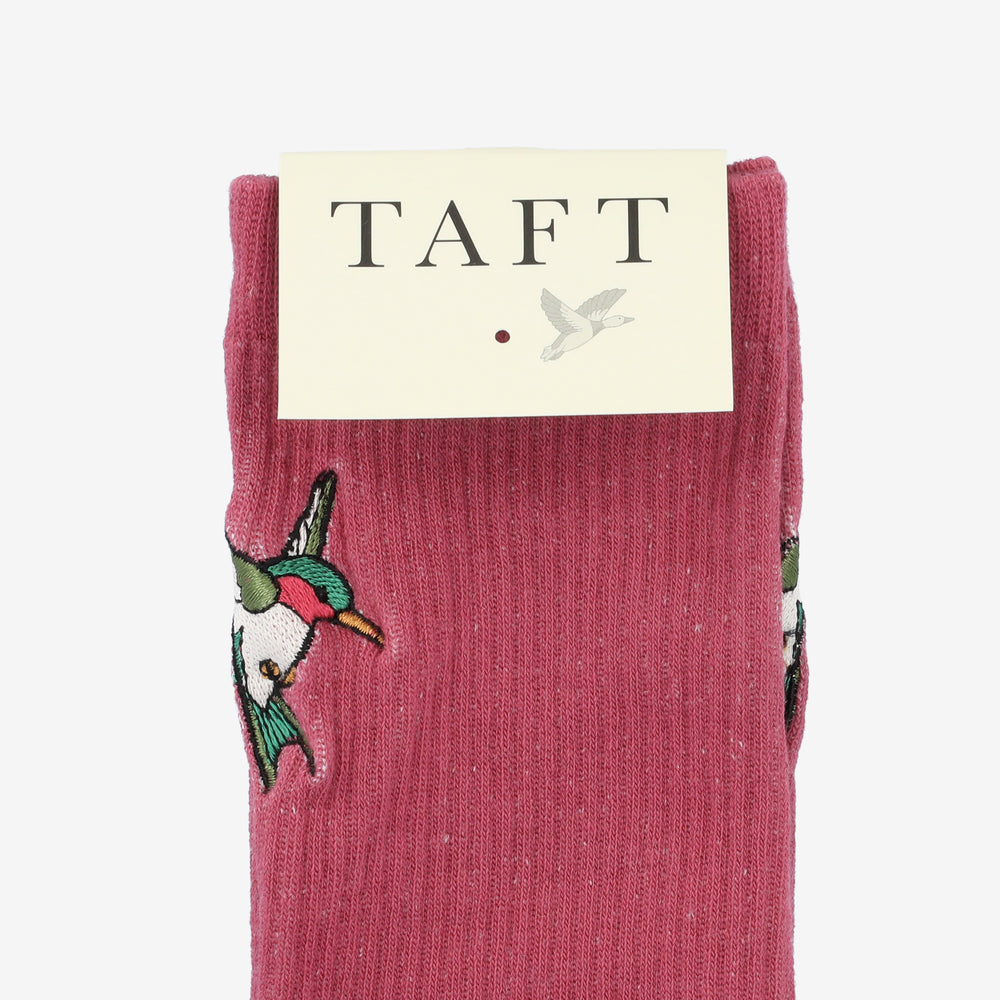 A pair of pink socks with embroidered birds, packaged under a label reading TAFT.