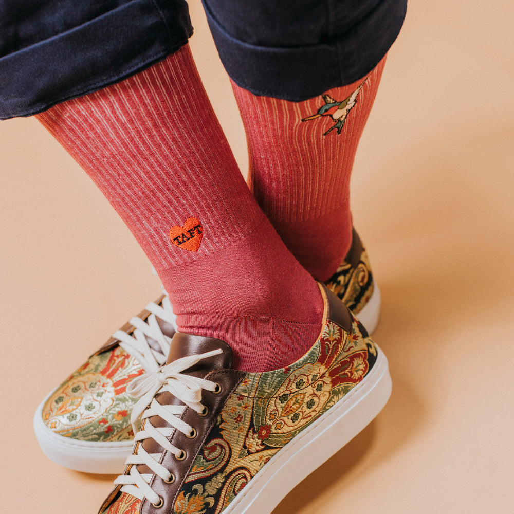 Person wearing red socks with patterns and embroidered designs, paired with ornate, patterned sneakers.