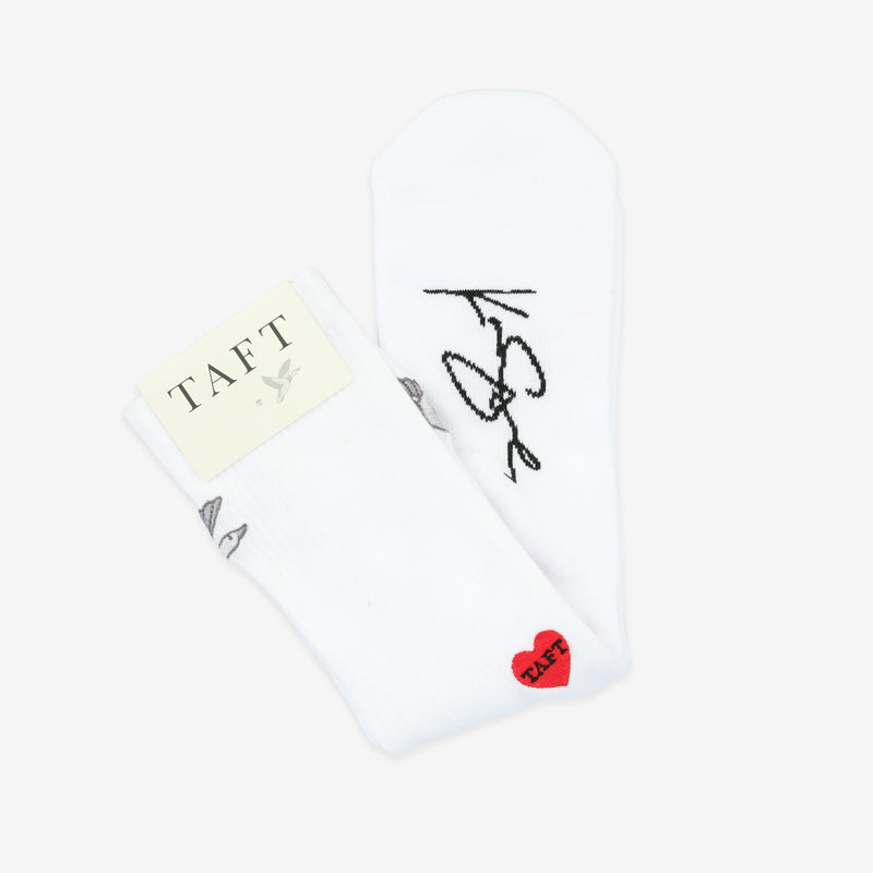 White socks with black cursive writing, a small red heart, and a tag labeled TAFT.