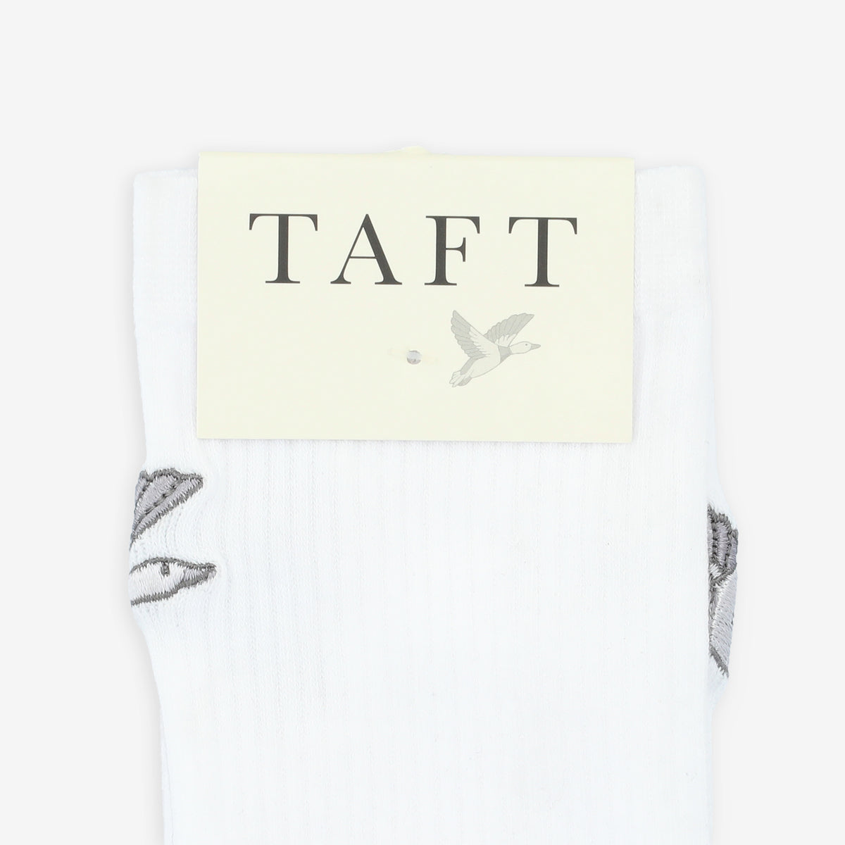 White socks with a label reading TAFT and featuring a small bird graphic. Partial images of birds are visible on the socks.