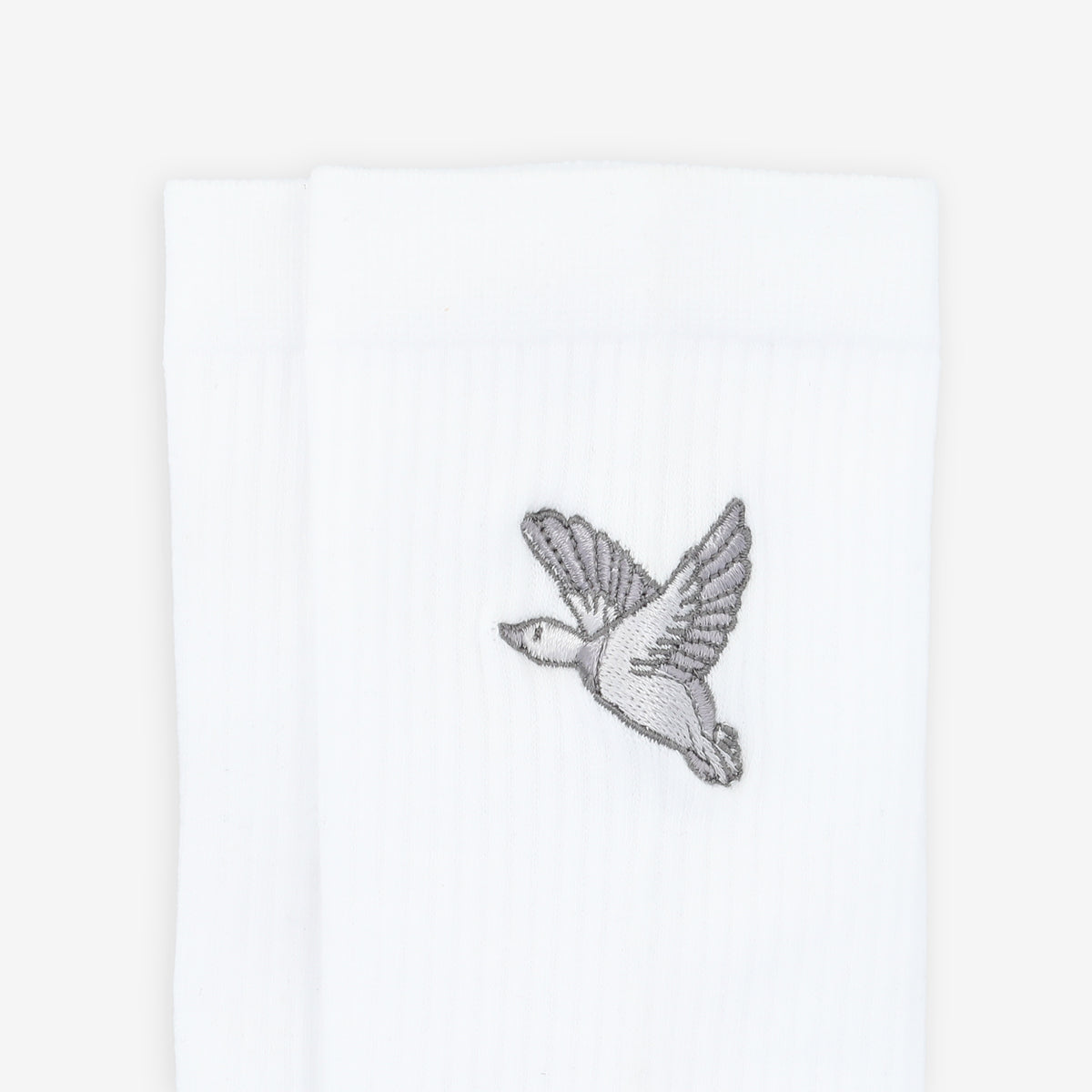 Close-up of white socks with a small embroidered image of a bird in flight.