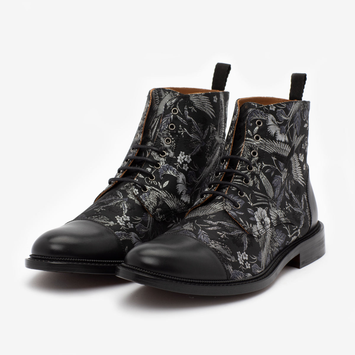 A pair of black leather boots with a floral pattern, black laces, and black toe caps.