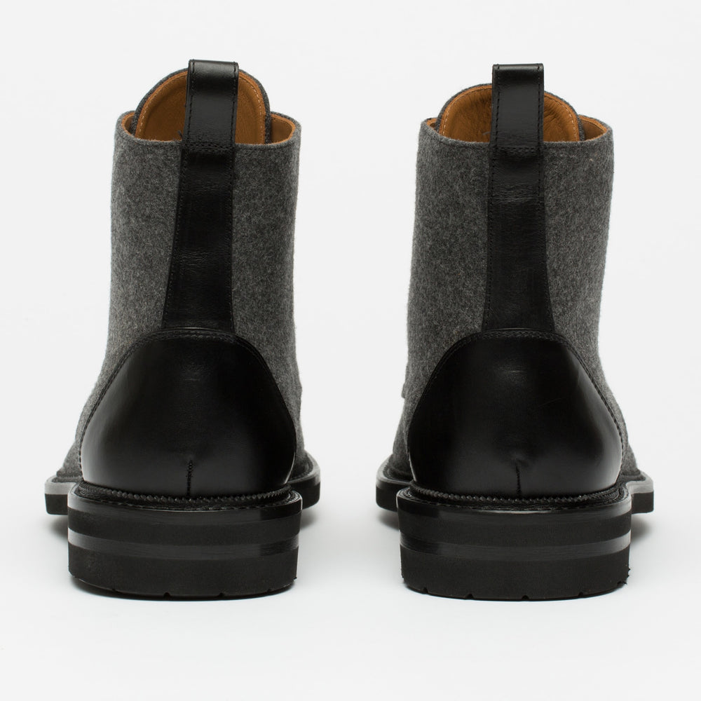 Rear view of two gray and black leather boots with black soles, standing upright side by side against a white background.