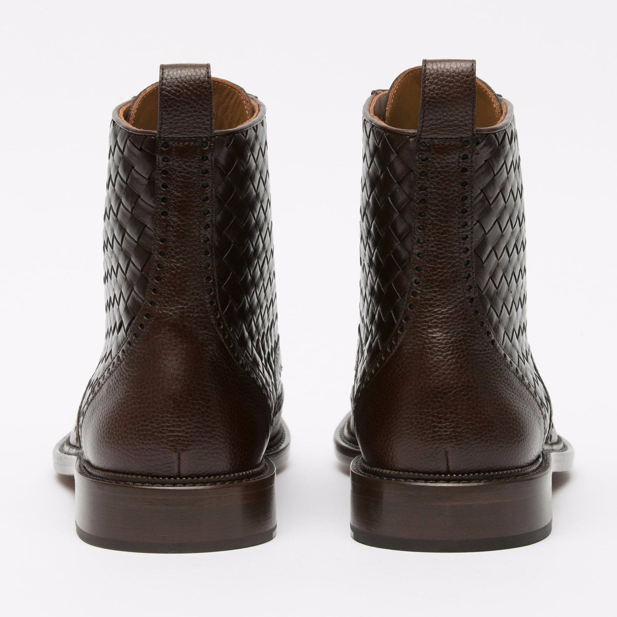 Rear view of a pair of dark brown leather boots with a woven pattern and textured details. The boots have sturdy heels and are positioned on a plain white background.