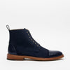 A side view of a navy blue leather and suede lace-up boot with a wooden sole against a plain white background.