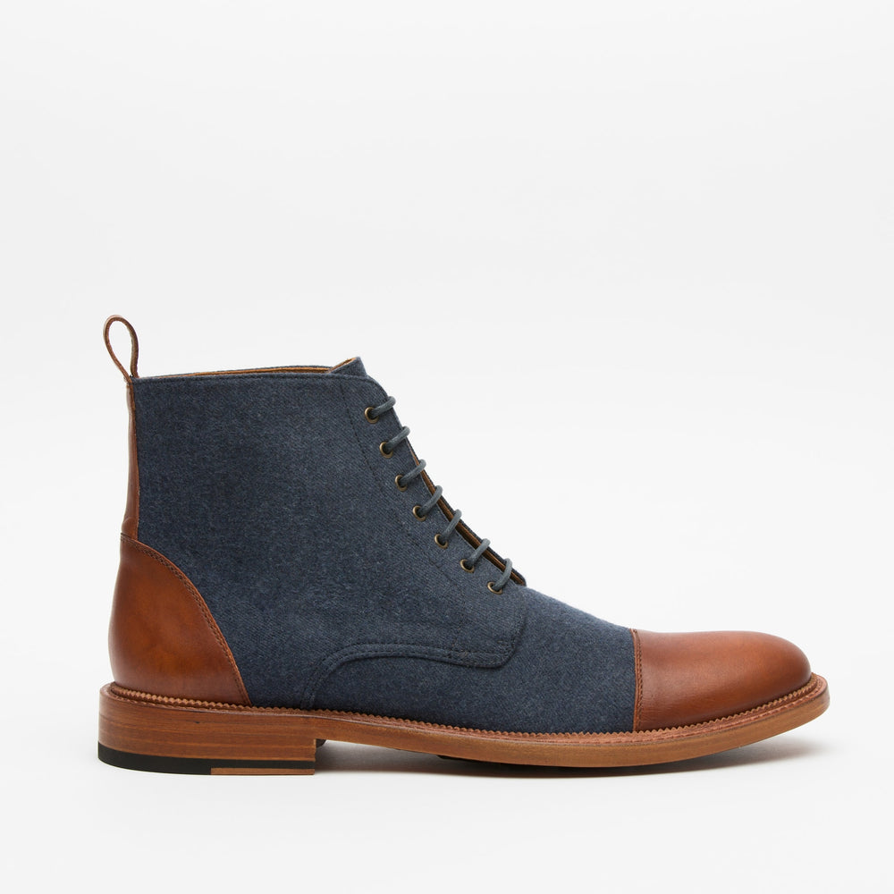 A men's high-top boot with blue fabric and brown leather detailing, featuring a blend of materials on the upper and a wooden sole.