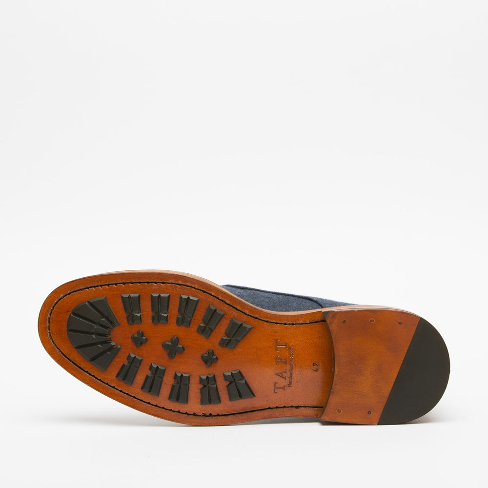 Bottom view of a single brown leather shoe sole with black rubber traction pads and the brand name TAFT stamped on it.