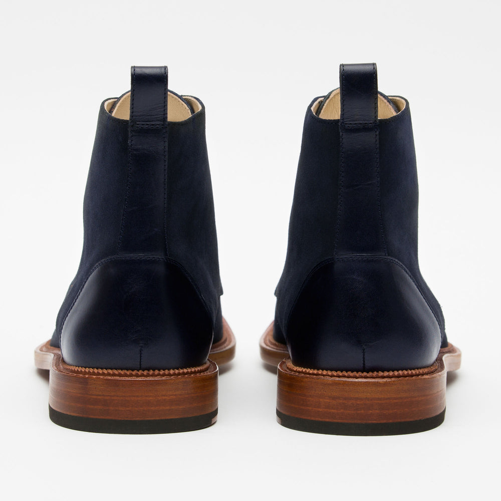 A pair of blue suede boots with brown wooden soles, shown from the back.