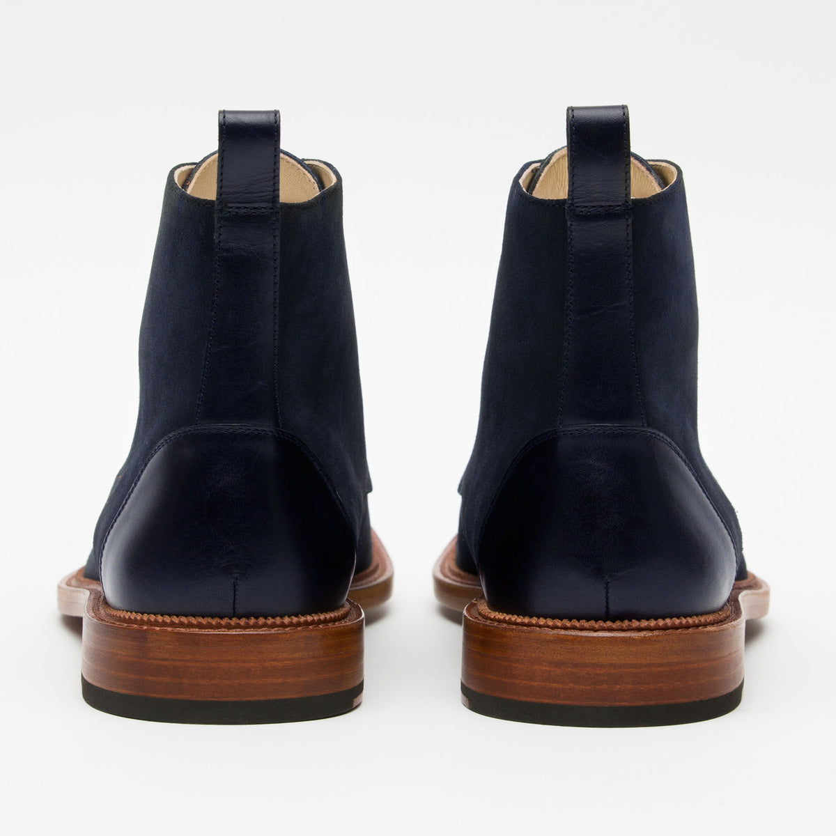 A pair of blue suede boots with brown wooden soles, shown from the back.