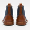 A pair of blue fabric boots with brown leather accents and pull tabs viewed from the back.