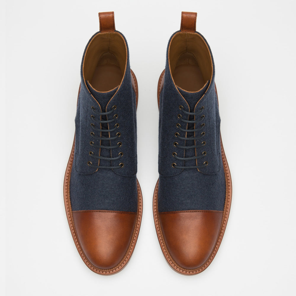 A pair of brown and navy lace-up ankle boots viewed from above, featuring brown leather toe caps, heel caps, and a brown leather trim, with navy fabric on the sides.