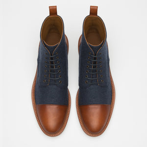 A pair of brown and navy lace-up ankle boots viewed from above, featuring brown leather toe caps, heel caps, and a brown leather trim, with navy fabric on the sides.