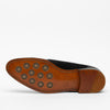 The image shows the bottom view of a black leather dress shoe with a tan sole featuring circular grip pads and detailed stitching. The brand name TAFT is imprinted on the sole.