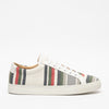 A low-top sneaker with a white sole, featuring a multicolored striped pattern on the fabric upper.