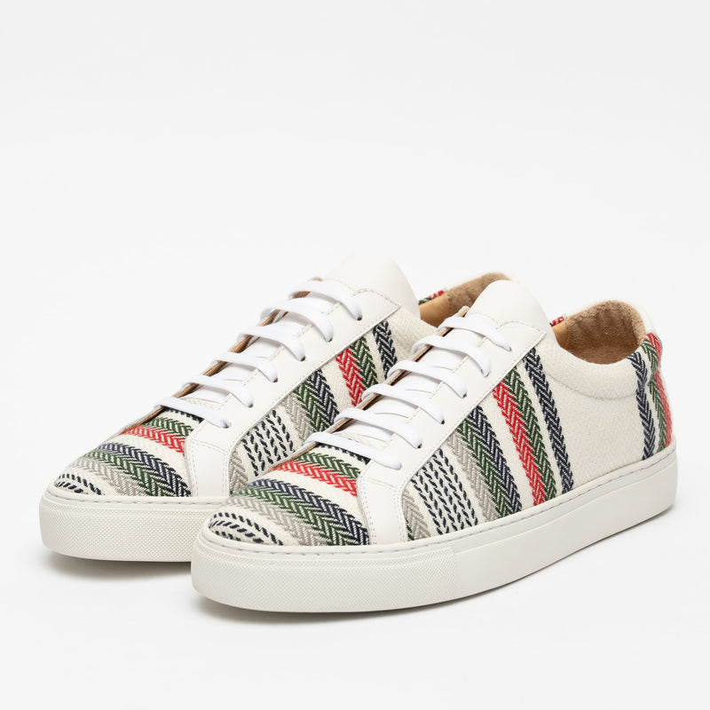 A pair of white sneakers with multicolored chevron-patterned fabric panels. They have white laces and thick white rubber soles.