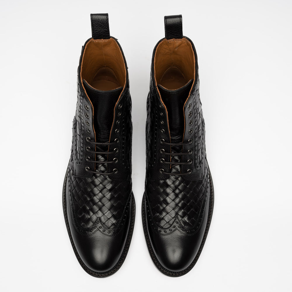 A pair of black leather dress boots with woven detailing, brogue toe design, and pull tabs, viewed from above on a white background.
