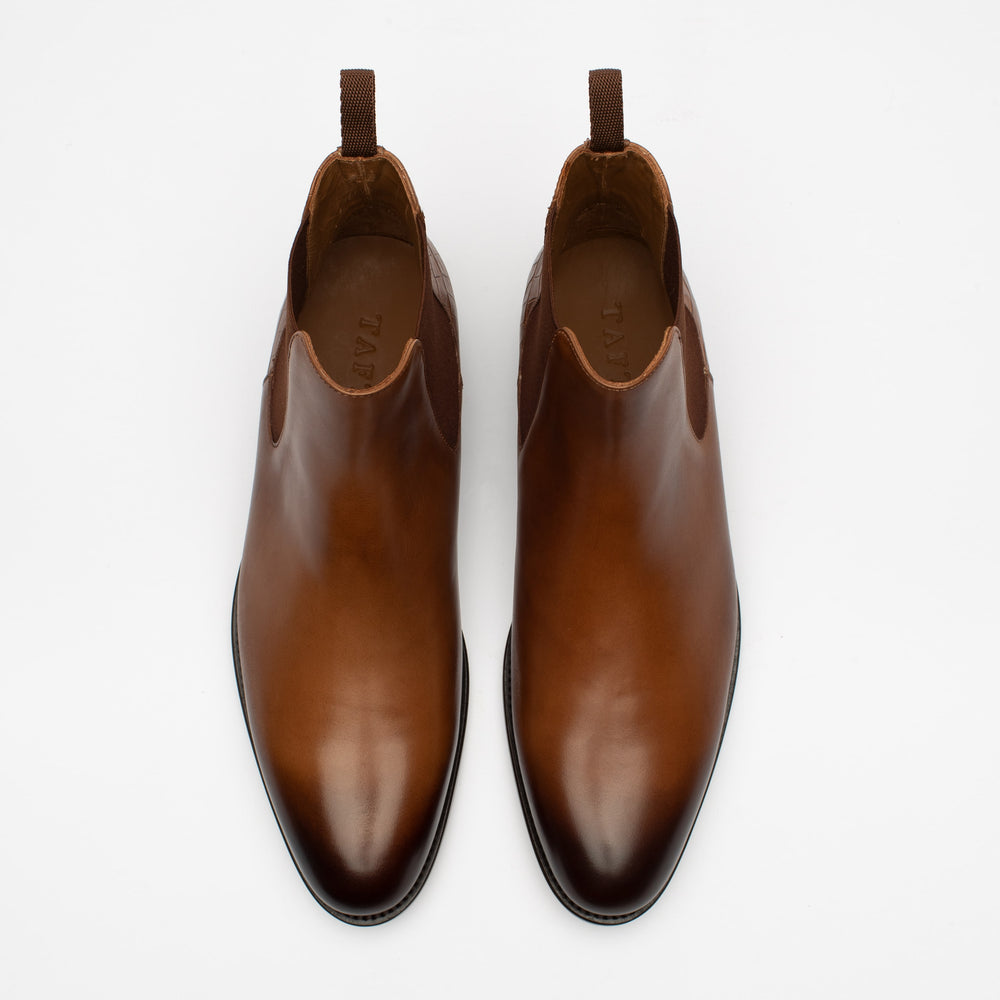 A pair of brown leather slip-on shoes viewed from above, with brown pull tabs at the back.
