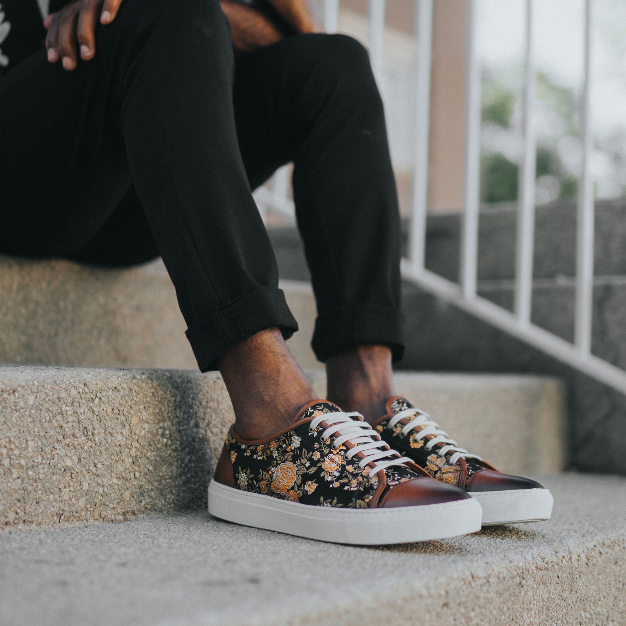 Jack Sneaker in Eden on Model sitting on concrete steps wearing black rolled jeans