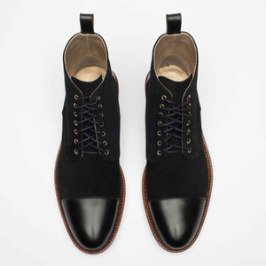 A pair of black leather boots with brown soles, featuring metal eyelets and black laces, placed side by side on a white background.